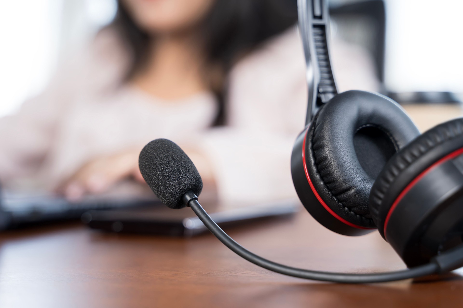 A person is using a microphone and a computer mouse. The person is wearing a headset.